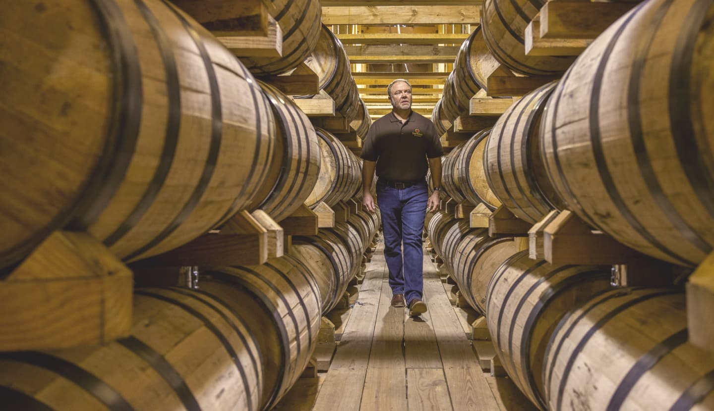 Master Distiller, Brent Elliot, walking through a warehouse full of bourbon barrels.