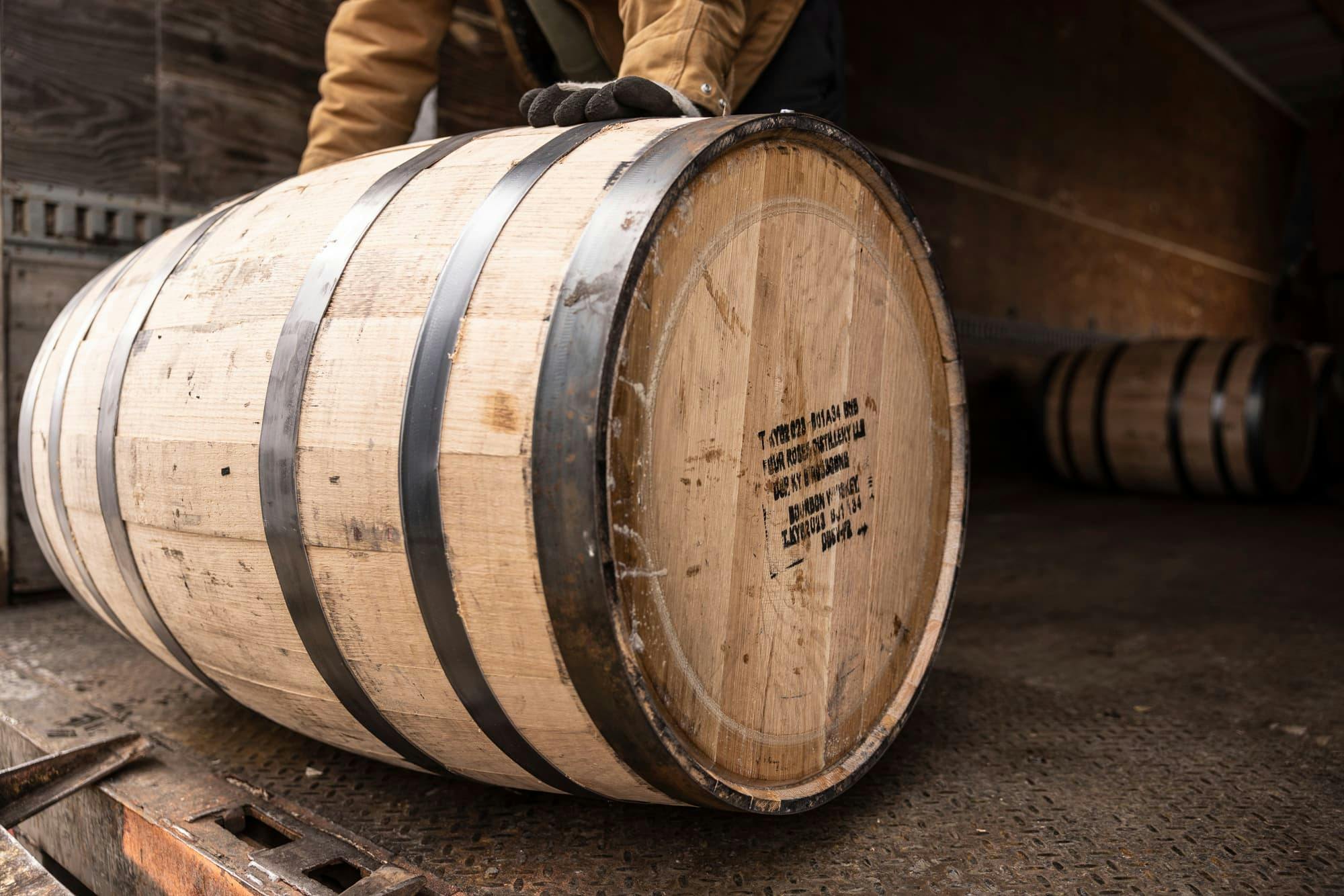 Four Roses team rolling a barrel of bourbon